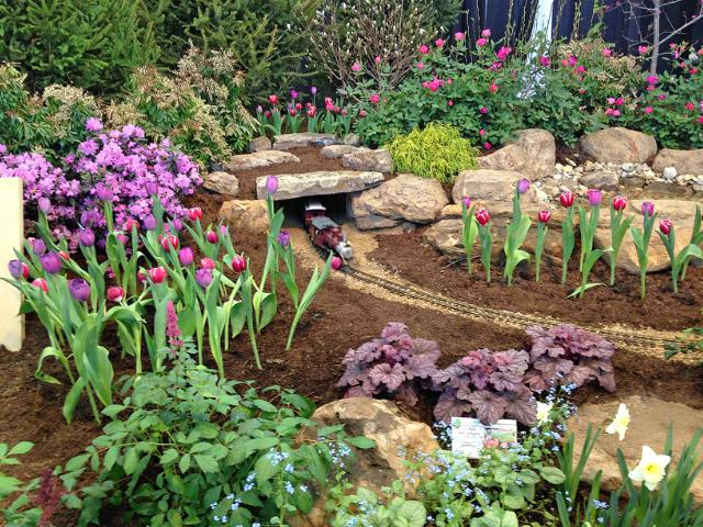 Flower bed with an electric train track and tunnel