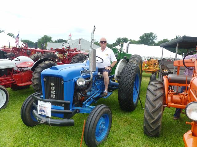 Driver seated on 1960's Blue Ford Tractor at Antique Tractor Display