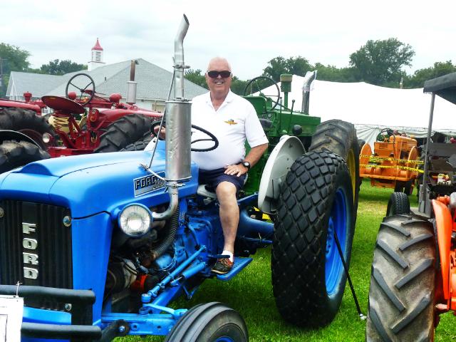 Closer Shot of Driver seated on 1960's Blue Ford Tractor at Antique Tractor Display