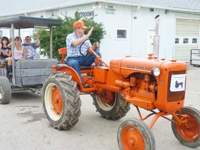 Orange 1947 Allis Chalmers D Tractor pulling Surrey with a Fringe on Top in Monday's Parade at the fair